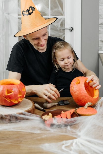 Parent with chld are carving pumpkin for halloween