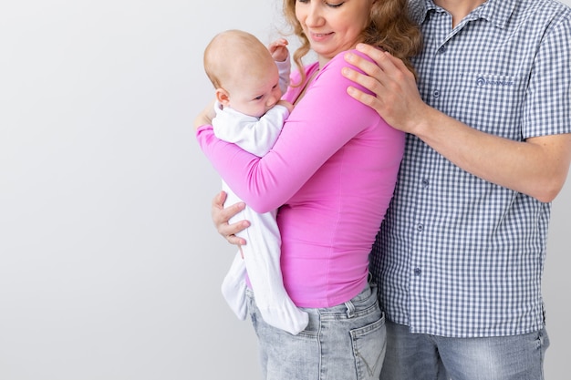 Parenthood, children and people concept - close up of young family holding baby on white background with copy space