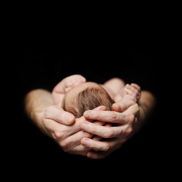 Parenthood concept Newborn baby on fathers hand on black background