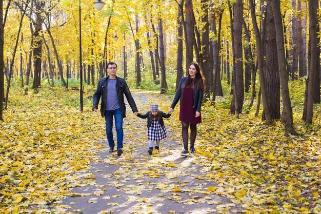 Concetto di genitorialità, caduta e persone - giovane famiglia felice nella sosta di autunno