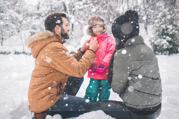 Parenthood, fashion, season and people concept - happy family with child in winter clothes outdoors