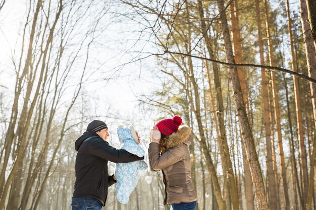 Концепция отцовства, моды, сезона и людей. счастливая семья с ребенком в зимней одежде на открытом воздухе