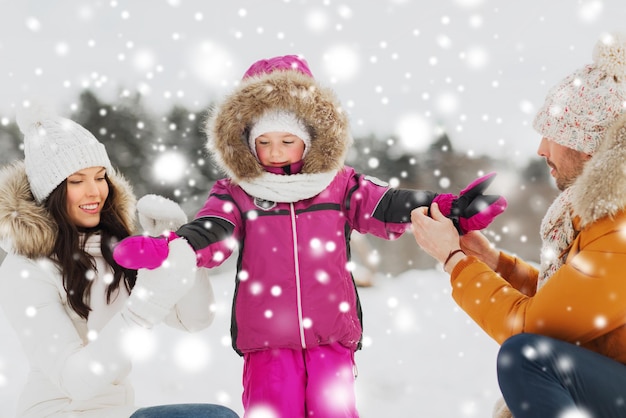 parenthood, fashion, season and people concept - happy family with child in winter clothes outdoors