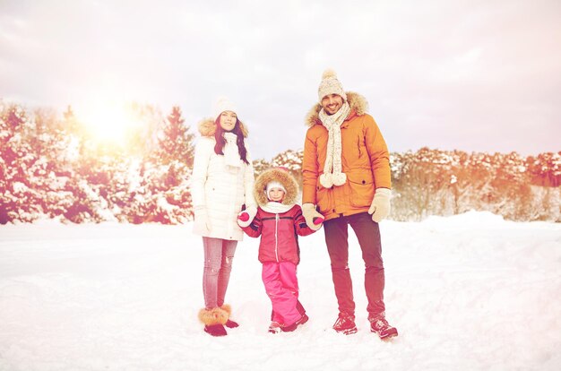 parenthood, fashion, season and people concept - happy family with child in winter clothes outdoors