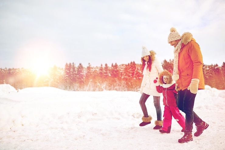 Photo parenthood, fashion, season and people concept - happy family with child in winter clothes walking outdoors