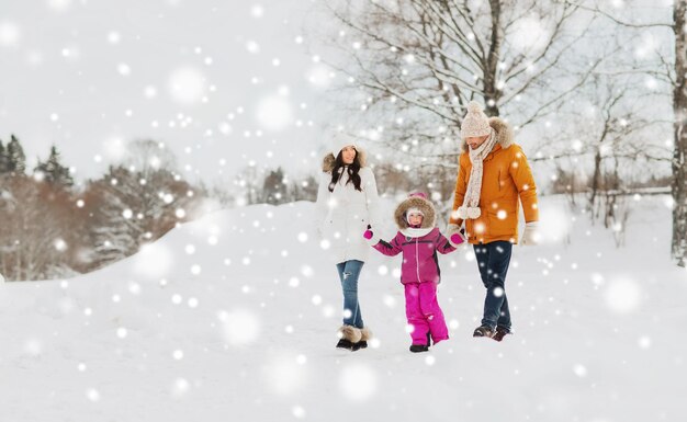 부모, 패션, 계절, 사람 개념 - 야외에서 걷는 겨울 옷을 입은 아이와 함께 행복한 가족
