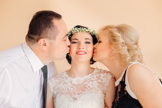 Parents are looking at their daughter girl in a wedding dress looks at the camera