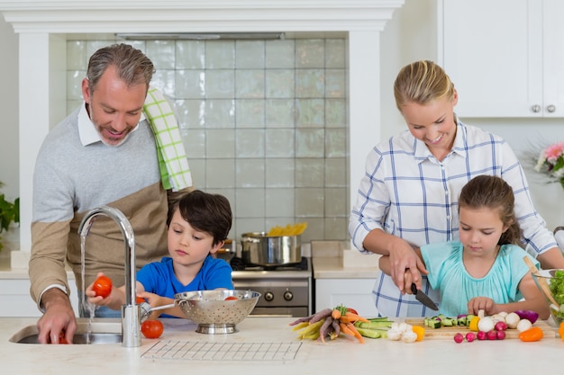 Parents assisting a kids to chop and clean the vegetables in kitchen