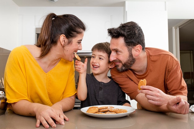 Photo parents and boy eating cookies