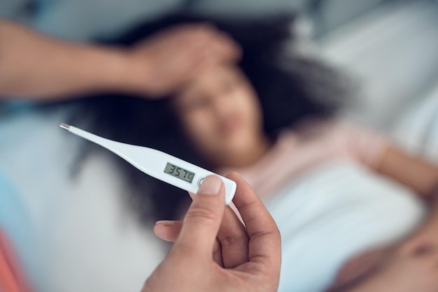 parents child and thermometer for symptoms of fever cold or virus in bedroom with worry concern or care father daughter and sick in home with temperature check and wellness for medical advice
