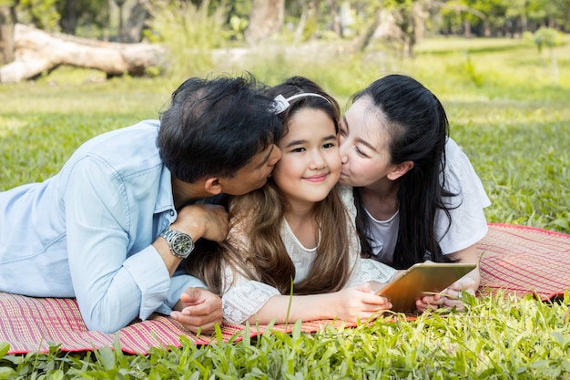 Parents and children are playing the tablet on the mat.