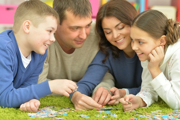 Genitori e bambini sdraiati sul pavimento e raccolgono pezzi di puzzle