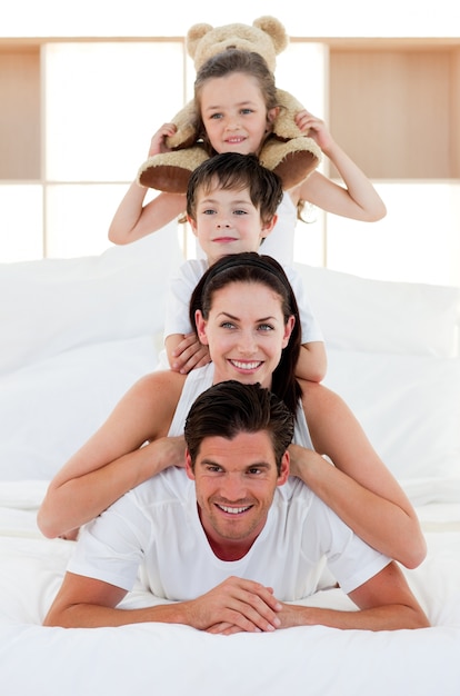 Parents and children playing on bed together 