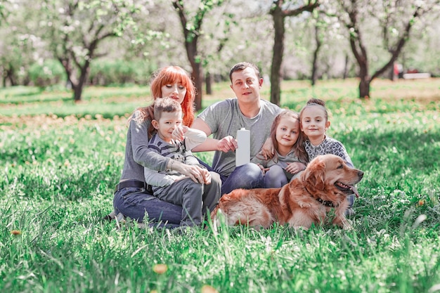 Parents, children and their pet sitting on the lawn on a summer day