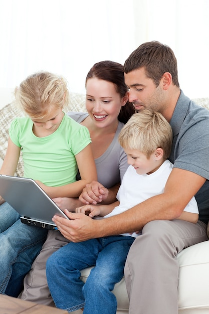 Parents and children using their laptop together sitting on the sofa