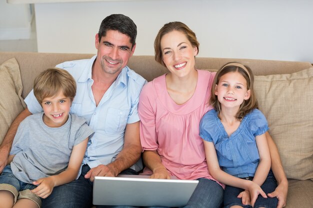 Parents and children with laptop on sofa