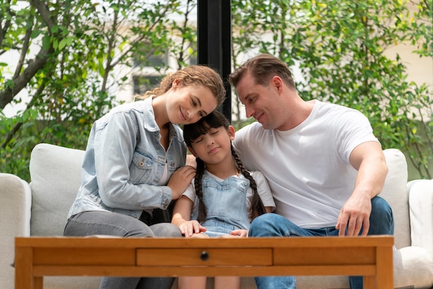 Parents comforting their daughter with loving hug helping her feel secure and protected from fear rest her head on shoulder Happy family love and child care support concept Synchronos