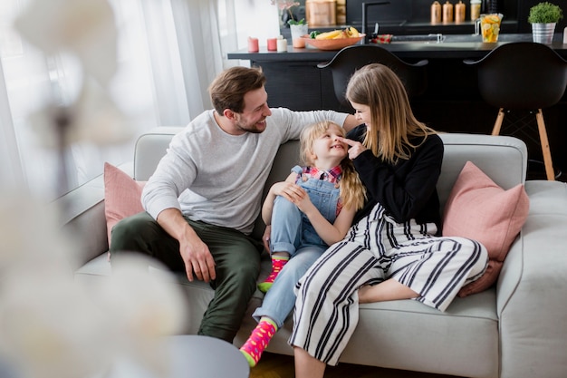 Photo parents cuddling with daughter on sofa