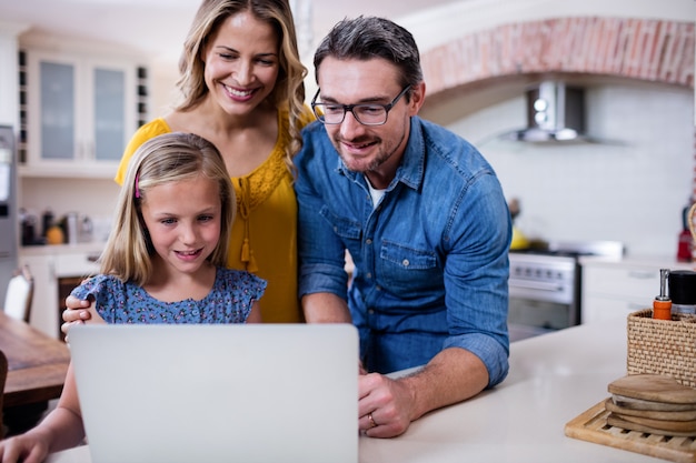 Foto genitori e figlia che utilizza computer portatile nella cucina