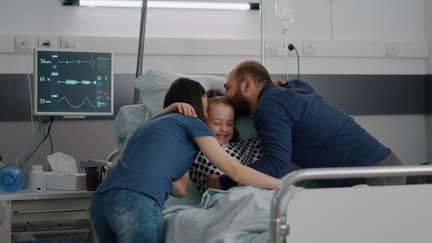 Photo parents embracing daughter in hospital