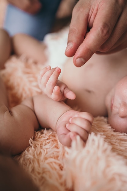 Parents gently hold small childrens hands closeup of the babys hand and parents parents care about t...