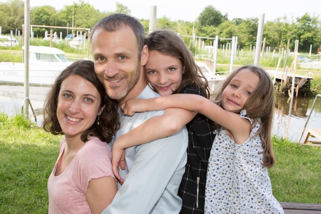 Parents Giving Children Piggyback Ride On Walk By Lake mother father and two daughter