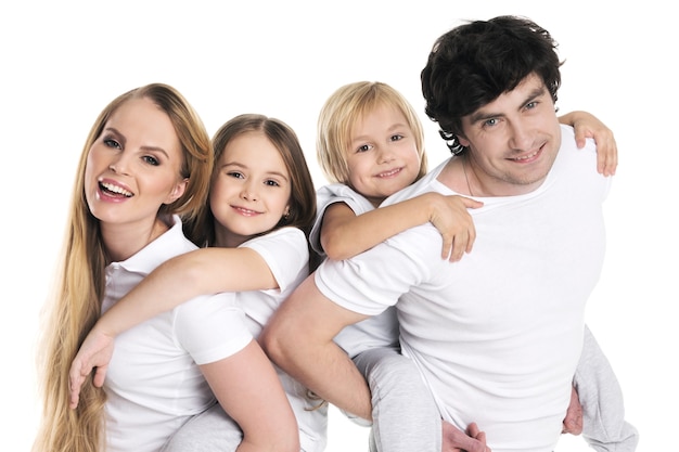 Photo parents giving two children piggyback rides smiling isolated on white wall