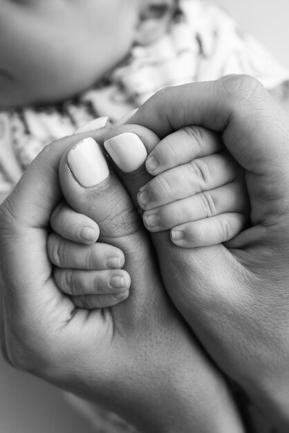 Руки родителей держат пальцы новорожденного ребенка Рука матери и отца вблизи держит кулак новорожденных детей Семейное здоровье и медицинская помощь Крошечные пальцы на черно-белой фотографии