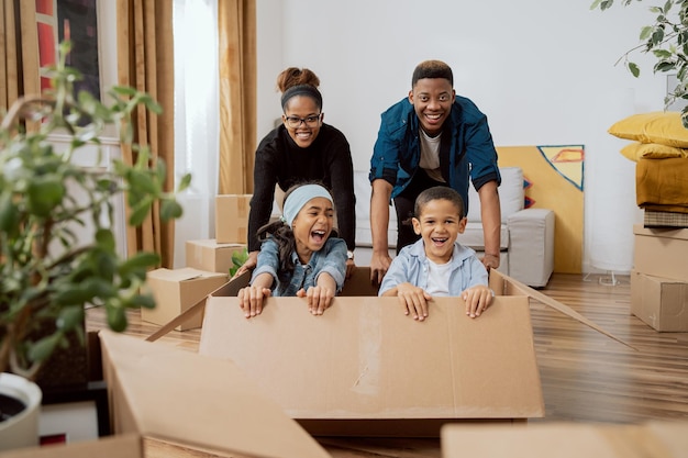 Parents have fun driving cute little son and beautiful daughter in cardboard box