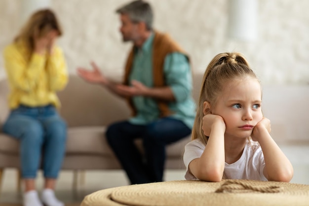 不幸な幼い娘が家に座っている間に喧嘩をしている両親