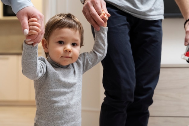 Photo parents holding kid's hands for his first steps