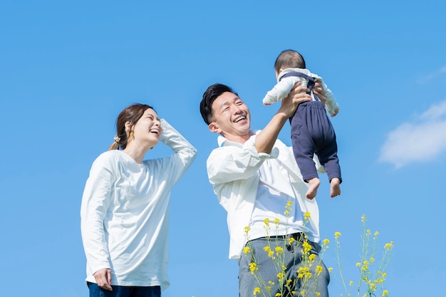 Parents holding their baby high under the blue sky