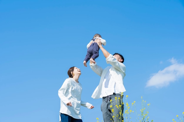 Photo parents holding their baby high under the blue sky