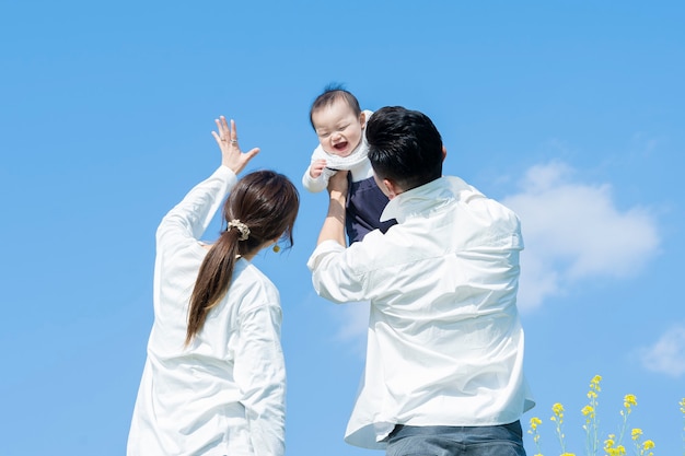 Parents holding their baby high under the blue sky