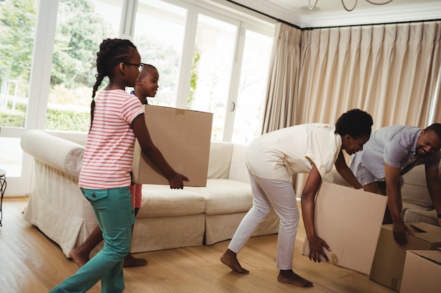 Parents and kids carrying cardboard boxes in living room