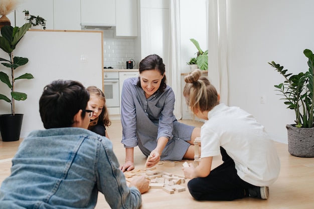 Parents and kids playing on the floor with blocks building a tower Low angle