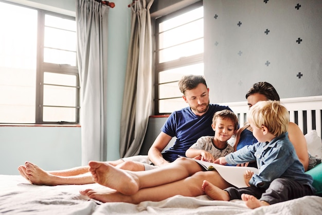 parents and kids sitting on bed at home