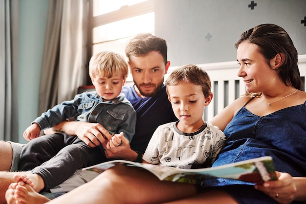 Photo parents and kids sitting on bed at home