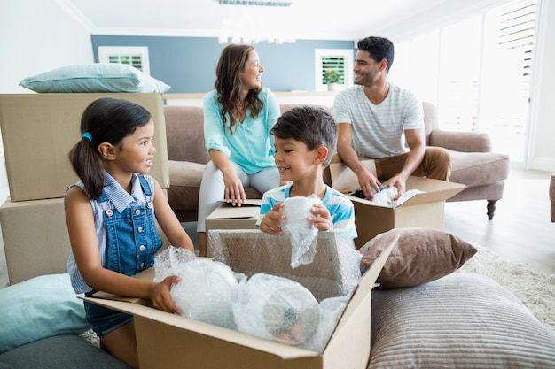 Parents and kids unpacking carton boxes in living room