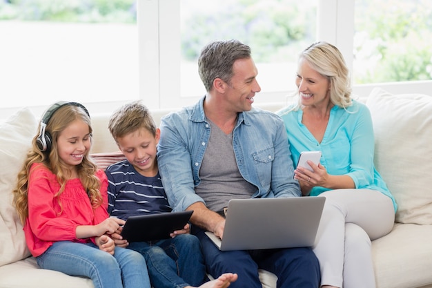デジタルタブレット、携帯電話、ラップトップを使用する親と子供
