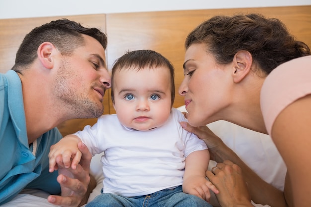 Parents kissing baby on cheek