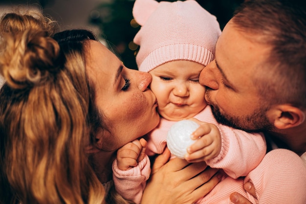 Parents kissing baby girl in pink