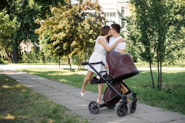 Parents kissing near their daughter in the babby carriage