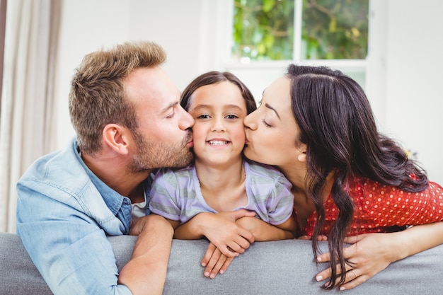 Parents kissing their daughter at home 