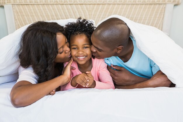 Parents kissing their daughter 