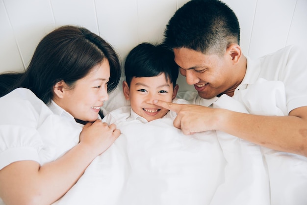 家でベッドに横たわっている可愛い息子を見ている両親