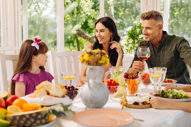 Parents looking at their cute daughter enjoying lunch outside