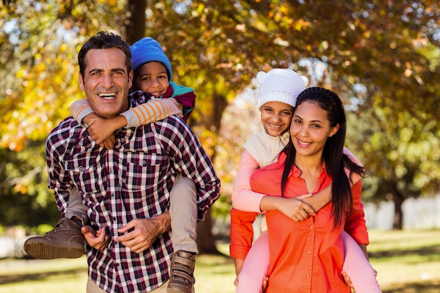 Parents piggybacking children at park