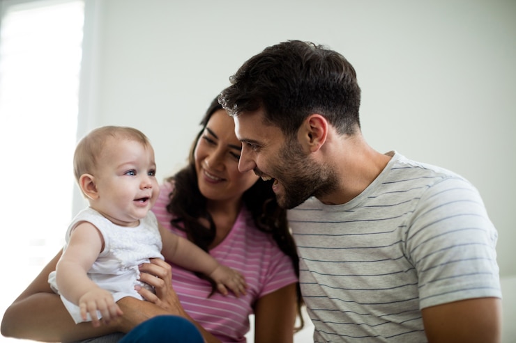 Photo parents playing with their baby girl in bedroom at home