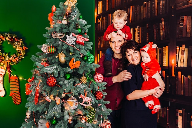 Parents pose with their little sons before a Christmas tree 